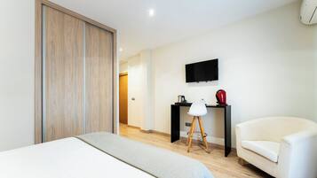 A hotel room with a bed, a desk, a chair, a TV, and a wardrobe.