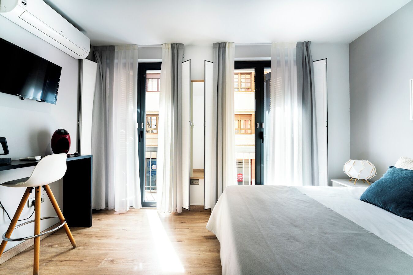 Una habitación de hotel moderna con cama, escritorio, silla y aire acondicionado.