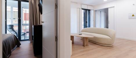 Une chambre d’hôtel moderne équipée d’un lit, d’un bureau, d’un canapé et d’une porte-fenêtre coulissante donnant sur un balcon.