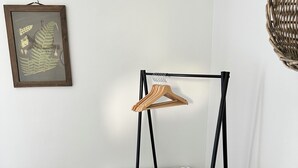 Ett rum med en hylla i trä, ett element, en korg av rotting och en inramad botanisk illustration.