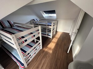 Ein Zimmer mit Etagenbetten, einem Oberlicht und Holzboden.