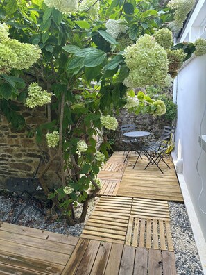 Eine Holzterrasse mit einer Steinmauer und einem kleinen Tisch mit Stühlen.