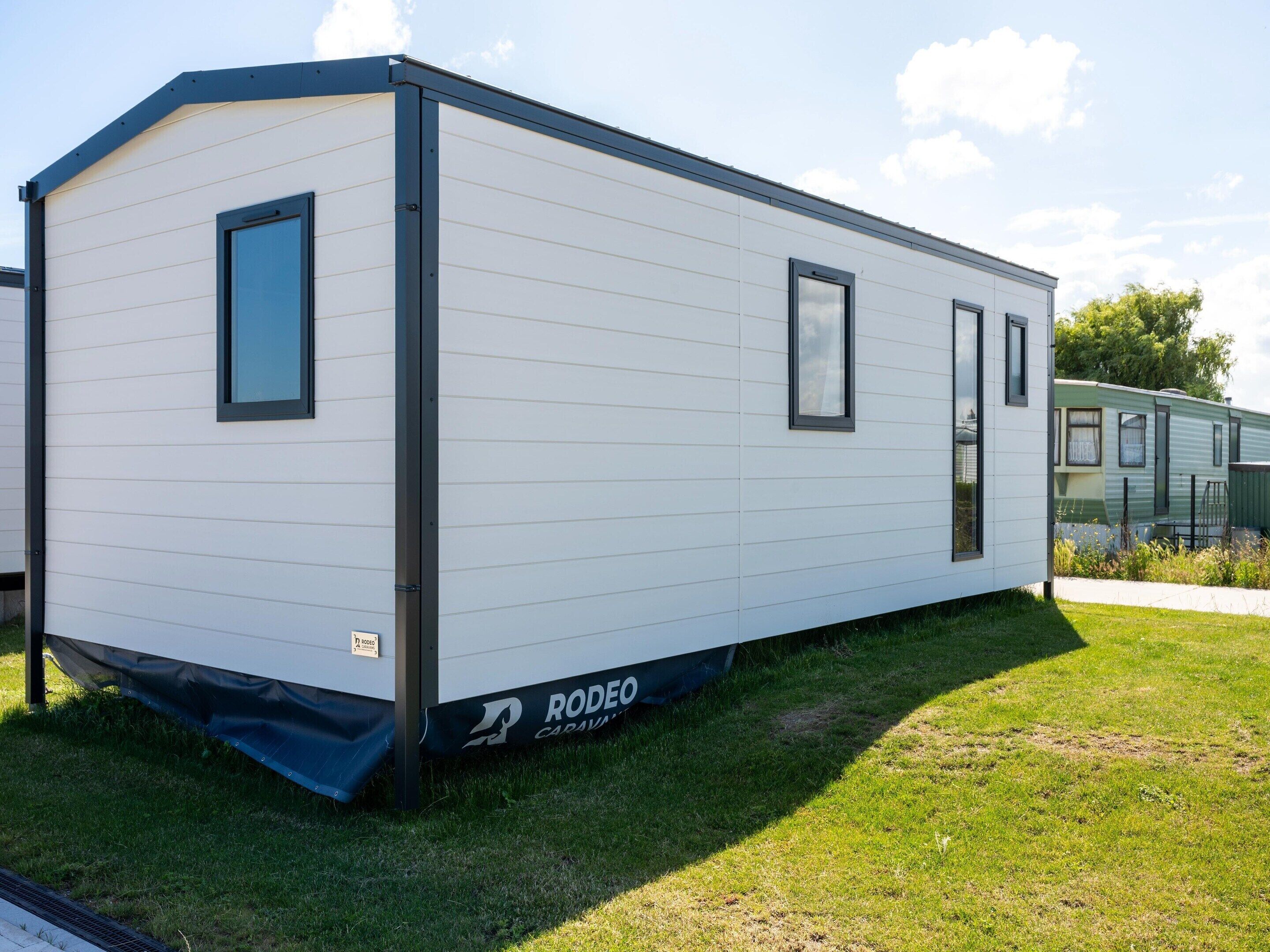 A single-story mobile home with a flat roof, two windows, and a door.