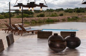 A poolside area with lounge chairs, a hanging light fixture, and rustic metal pots. - Casa de la Presa 3 (POLOKWANE)