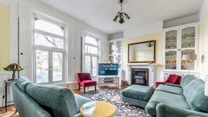 Een woonkamer met een open haard, een televisie en een boekenkast.