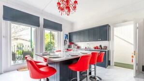 Een moderne keuken met een centraal eiland, rode barkrukken en een kroonluchter.