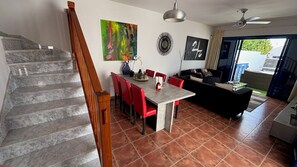 A modern living room with a dining area, a staircase, and a view through a glass door. - Villa Erimar in cozy Playa Blanca (Playa Blanca)