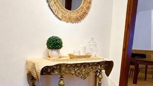 Ein Zimmer mit einem runden Spiegel, einem kleinen Tisch mit Dekoration und zwei gewebten Körben auf einem Teppich.