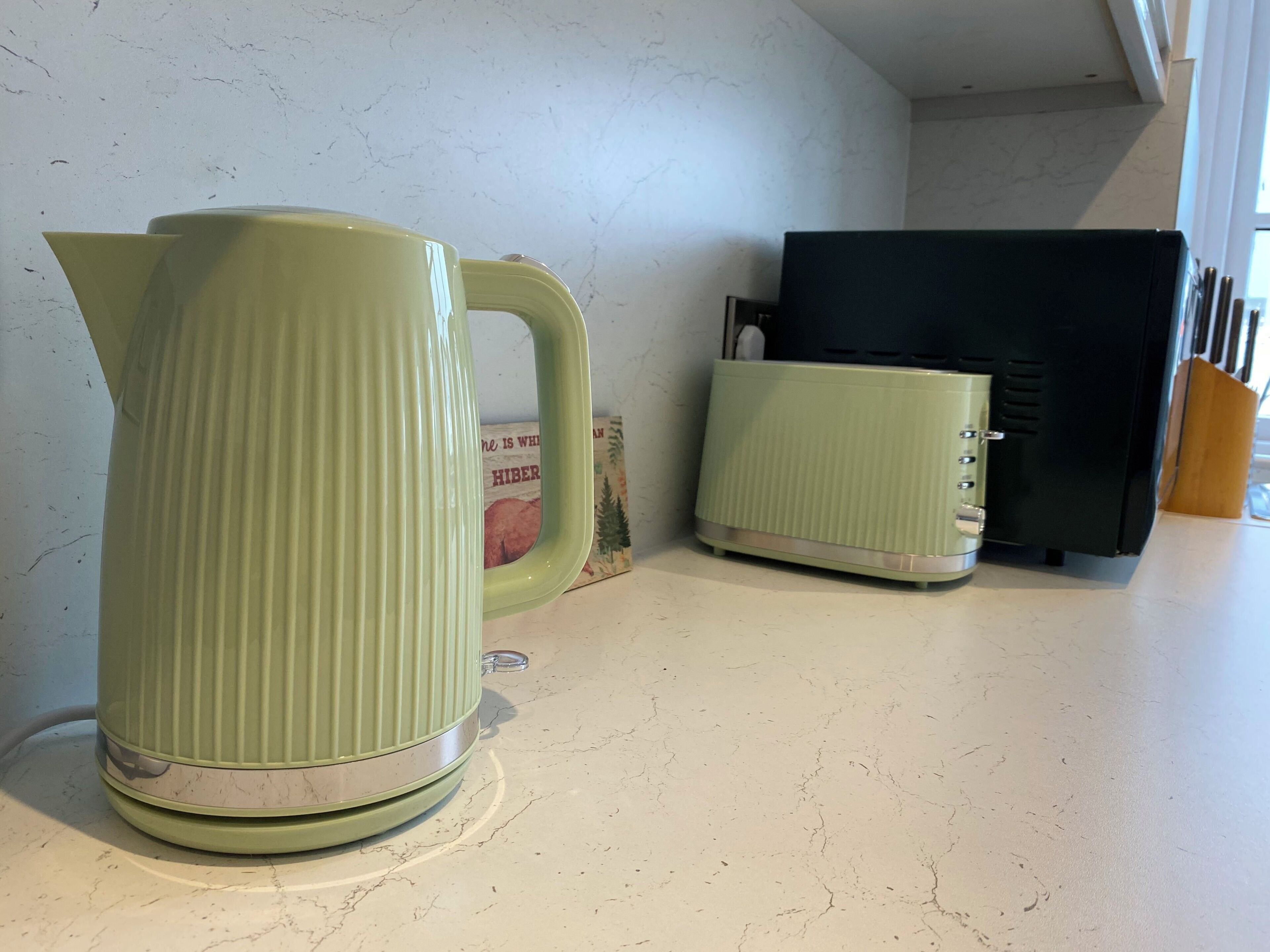 A kitchen with a kettle and a toaster on the counter.