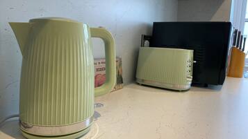 Een keuken met een waterkoker en een broodrooster op het aanrecht.