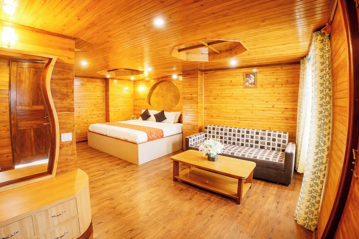 Een houten interieur met een bed, bank en een houten kast.