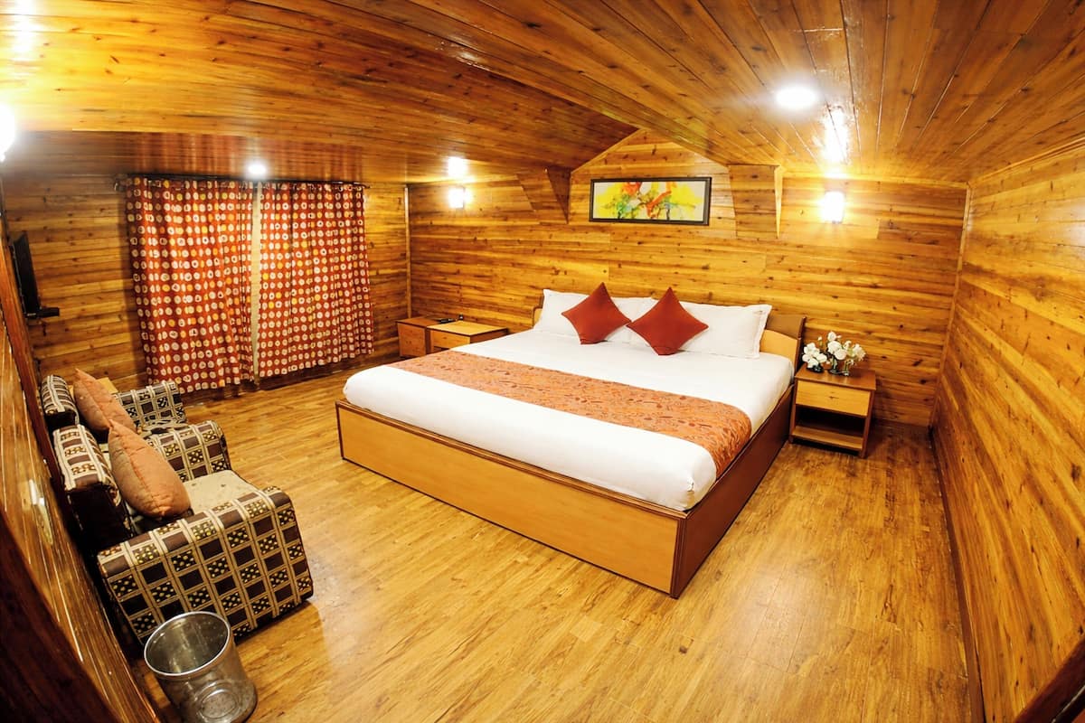 Een kamer met houten lambrisering, een bed, nachtkastje, stoel en een klein tafeltje.