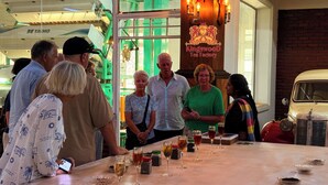 A group of people at a tasting event with wine glasses on a table, a vintage car, and a sign for 'Kingswood Tea Factory'. - Kingswood Tea Factory (Ramboda)