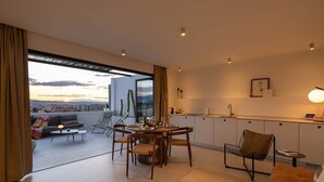 Ein moderner Wohnraum mit Essbereich, Küche und großem Fenster mit Blick auf die Stadt.