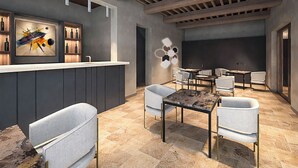 A modern bar area with a counter, seating, and artwork. - Tenuta Golo (Montepulciano)