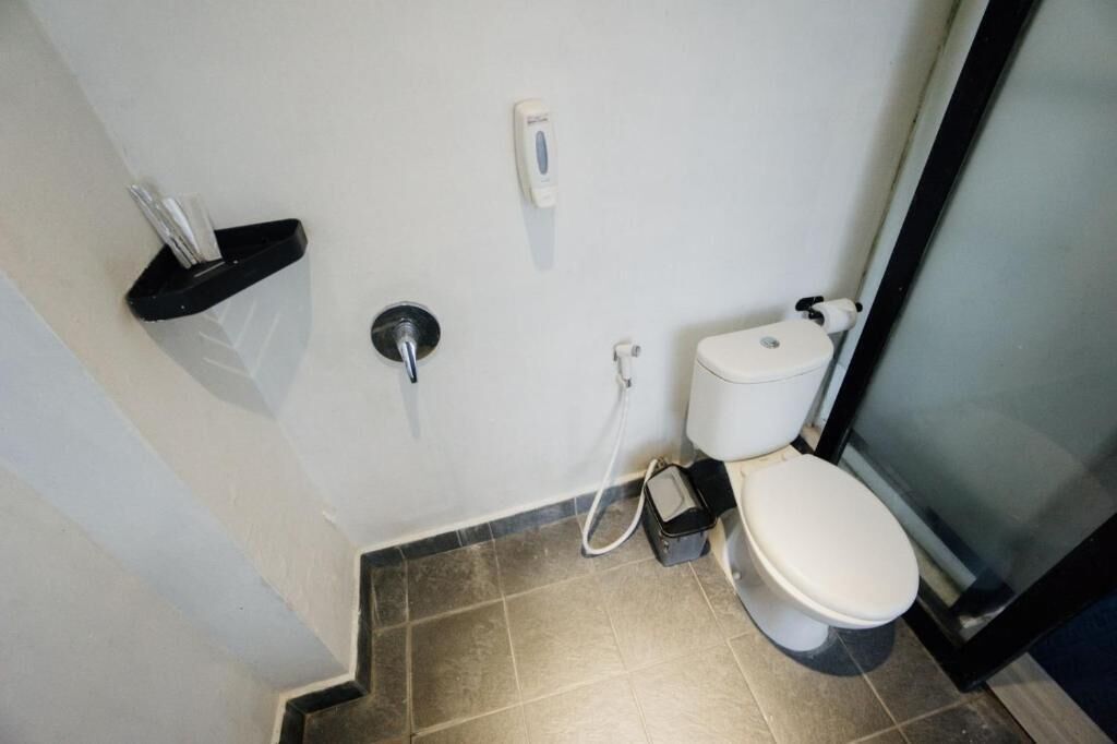 Une salle de bain équipée de toilettes, d’un sèche-mains et d’un distributeur de serviettes en papier.