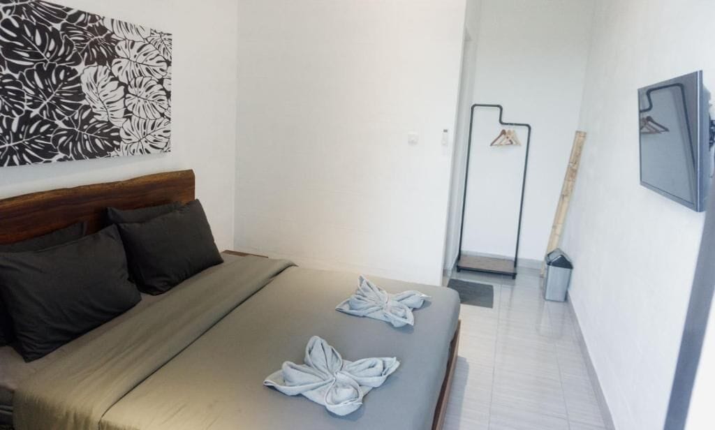 Une chambre d’hôtel comprenant un lit, une tête de lit, un téléviseur fixé au mur et une porte donnant sur une autre pièce.