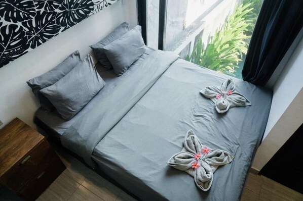 Una cama con ropa de cama gris, almohadas y dos toallas dispuestas en un diseño floral.
