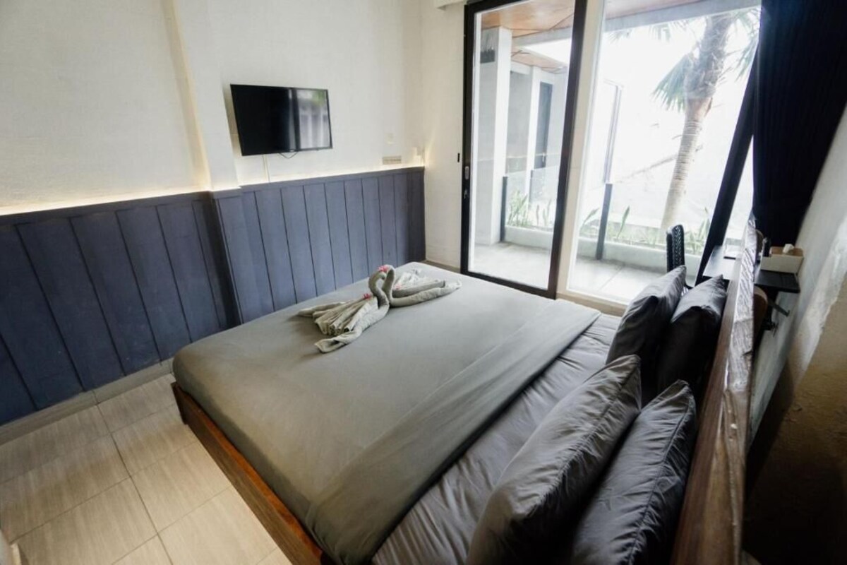 A bedroom with a bed, a television mounted on the wall, and a sliding glass door leading to an outdoor area.