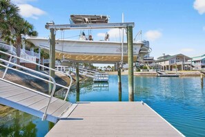 A dock with a boat, a wooden walkway, and a clear blue sky. - All The Phils by Brunswick VR: 5BR/3BA Canal Home, Sleeps 20, Steps from Beach (Ocean Isle Beach)