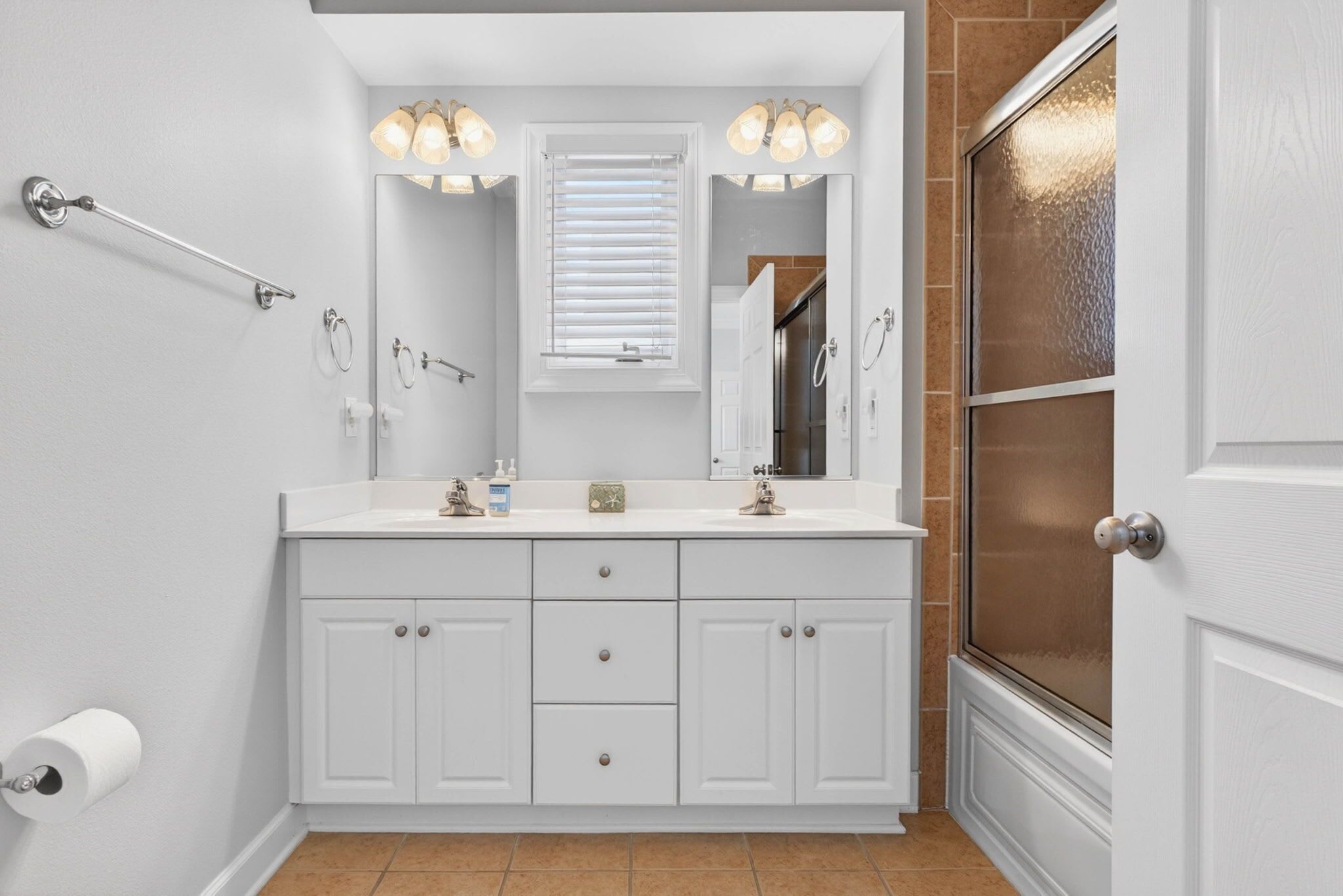 A bathroom with a white vanity, a mirror, a towel rack, a shower, and a glass door.