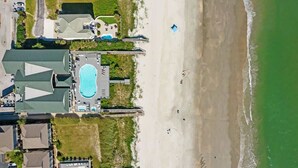 An aerial view of a coastal hotel with a swimming pool, beach access, and a parking area. - Chonky Waves by Brunswick VR: 4BR Condo w/ Ocean Views & Resort Amenities (Ocean Isle Beach)