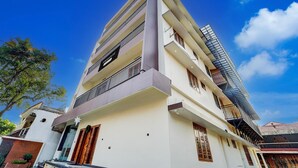 A multi-story building with balconies, a visible sign, and a clear sky. - Super Townhouse Kalady (Aluva)