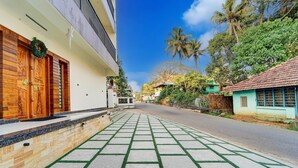 A residential street with a paved walkway, wooden doors, and a green wreath. - Super Townhouse Kalady (Aluva)