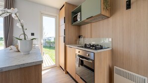 A modern kitchen with wooden cabinets, a built-in microwave, and a gas stove. - Caravan Bredene by the sea (Bredene)