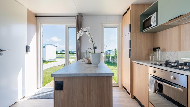 A modern kitchen with a central island, built-in appliances, and a view to the outdoors. - Caravan Bredene by the sea (Bredene)