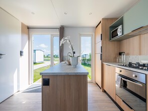 A modern kitchen with a central island, built-in appliances, and a view to the outdoors. - Caravan Bredene by the sea (Bredene)