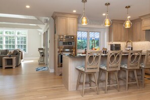 Une cuisine moderne avec des meubles en bois, des appareils en acier inoxydable et des luminaires suspendus.