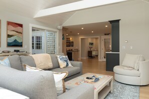 Una sala moderna con un sofá gris, un sillón blanco y una mesa de centro con objetos decorativos.