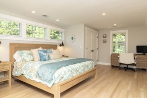 A bedroom with a wooden bed, a desk, a chair, and a television. - No crowds after Labor Day Week on Cape Cod  at Old Silver Beach (Falmouth)