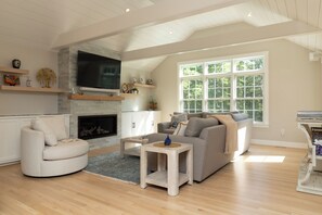 Una sala de estar moderna con chimenea, televisor y un amplio ventanal.