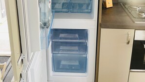 Ein offener Kühlschrank mit mehreren durchsichtigen Schubladen und einem Gefrierfach.