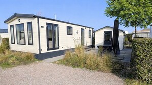 Ein eingeschossiges Mobilheim mit flachem Dach, großen Fenstern und einer kleinen Veranda.