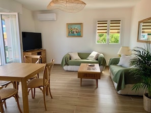 A living room with a wooden table, chairs, a sofa, a TV, and a painting on the wall. - Collioure—sea view, AC, terrace, garden, private garage, within walking distance of downtown—sleeps 4 (Collioure)