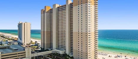 Un hotel de gran altura con varias plantas, vista al mar y un estacionamiento.