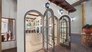 Un pasillo interior con arcos, una zona de recepción y una planta grande en maceta.