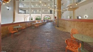 Un patio interior amplio con suelo de ladrillo, varios niveles de balcones y guirnaldas luminosas.