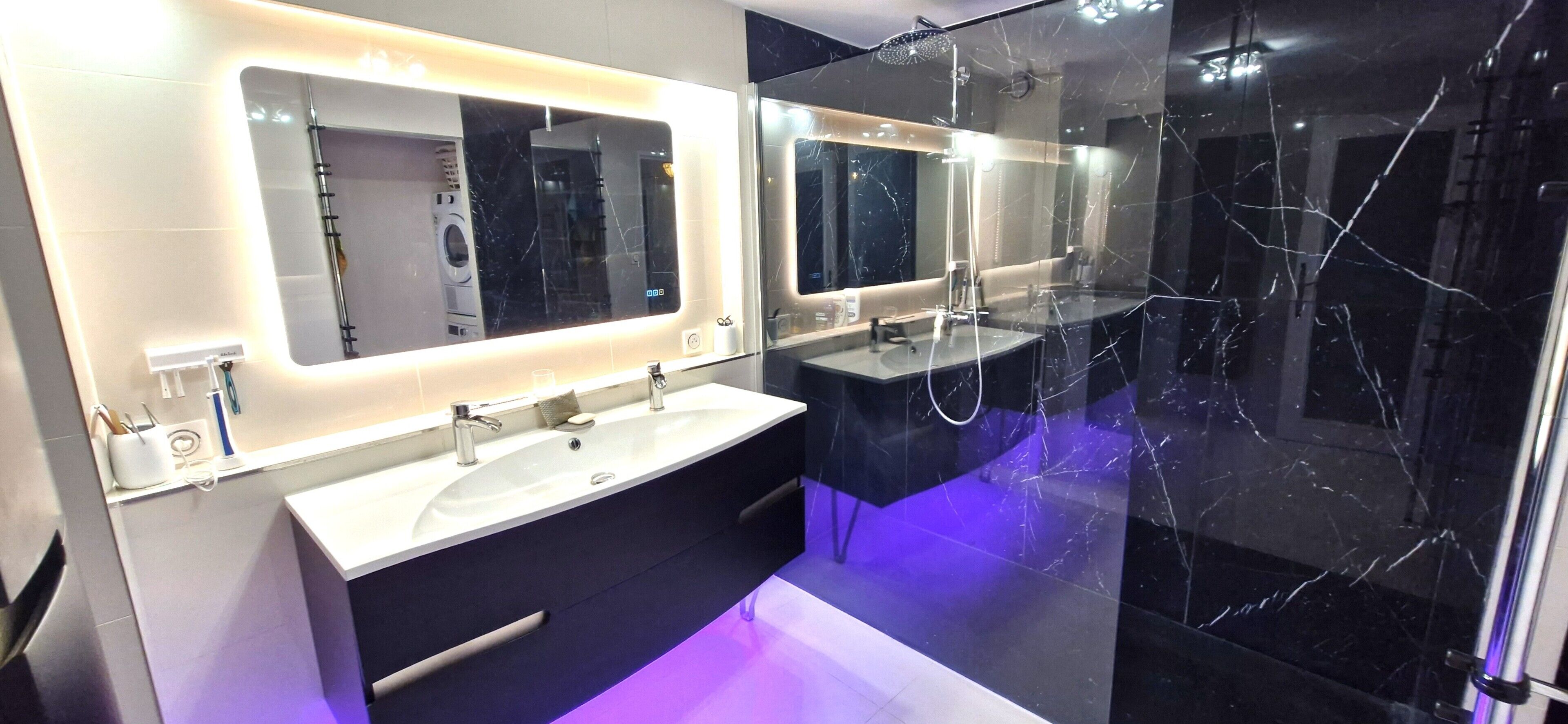 Un bagno moderno con un grande specchio, due lavabi, una doccia e un pavimento in marmo.