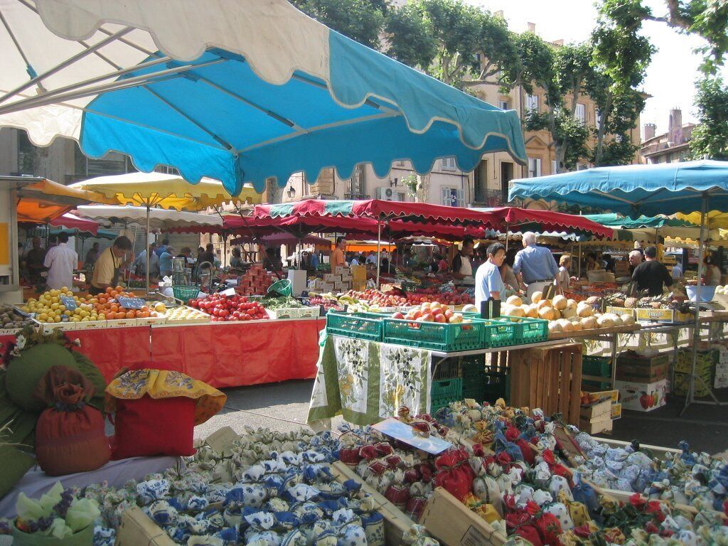 Un mercato all'aperto con diverse bancarelle che vendono frutta, verdura e fiori.