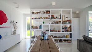 Un interior moderno con una mesa de madera, estanterías blancas con diversos objetos y una decoración floral roja.