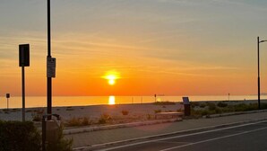Un atardecer sobre una playa con una carretera al frente.