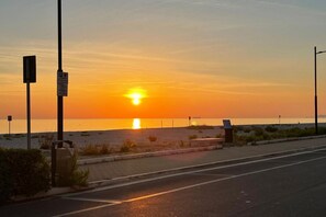 Un atardecer sobre una playa con una carretera al frente.