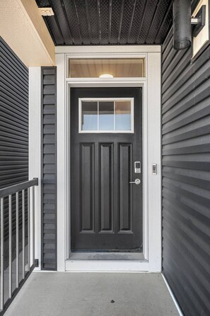 A black front door with a small window above it, a metal handle, and a doorbell. - Luxurious 4BR Home | Near Banff | YYC | Garage (Calgary)