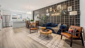 A modern living room with a sofa, chairs, a coffee table, and a kitchen in the background. - Luxurious 4BR Home | Near Banff | YYC | Garage (Calgary)