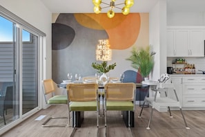 Een eetruimte met een moderne tafel, stoelen en een neonbord.