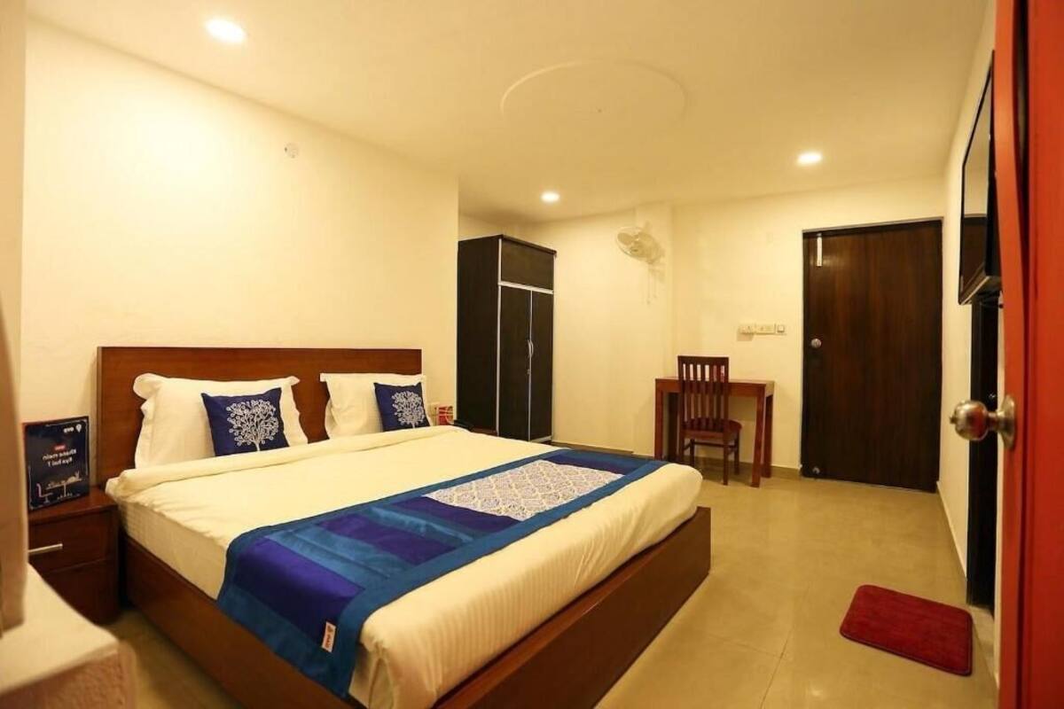 A hotel room with a bed, a desk, a chair, a wardrobe, and a door.